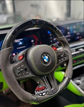 Volante BMW de fibra de carbono con empuñaduras de gamuza gris y costuras verdes.