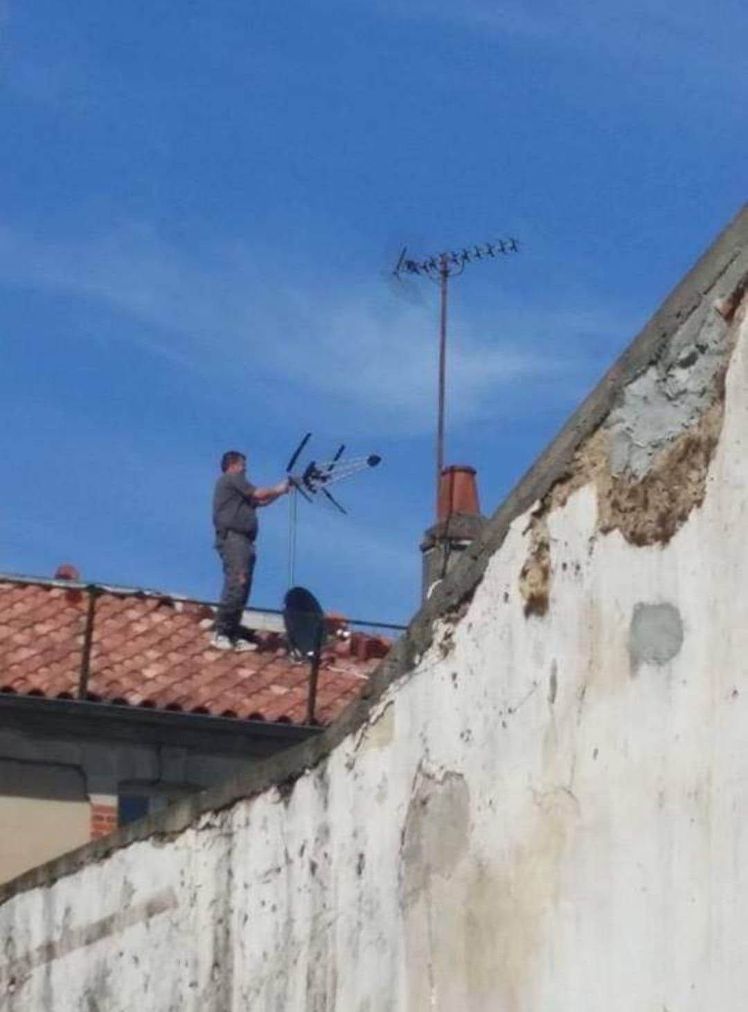 Un homme qui pose une antenne TV