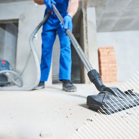 Professionnel en bleu de travail aspirant des gravats