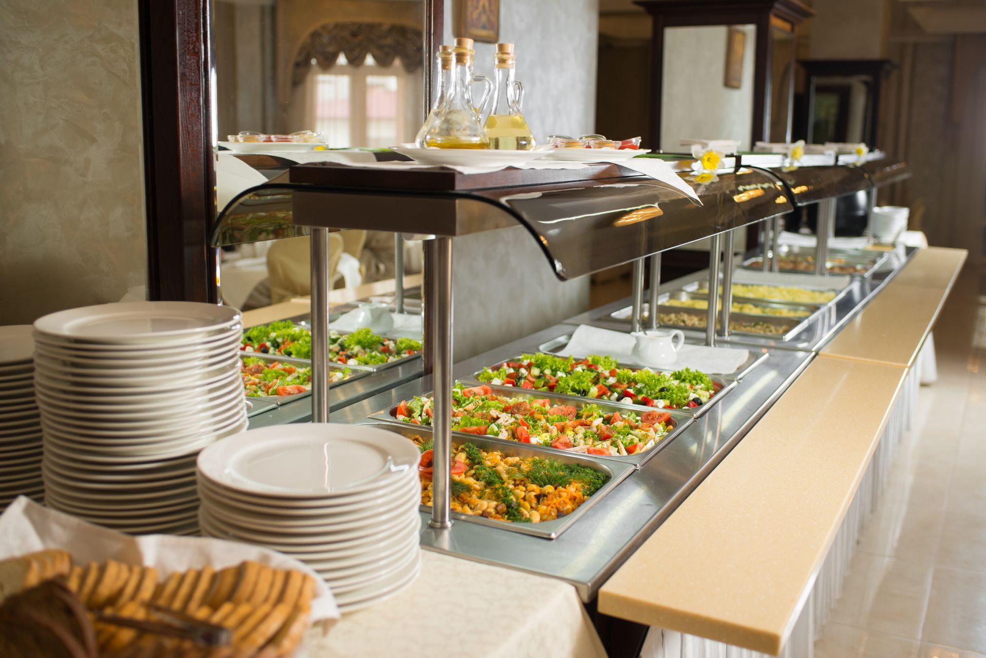 Buffet de salades avec des piles d'assiettes.