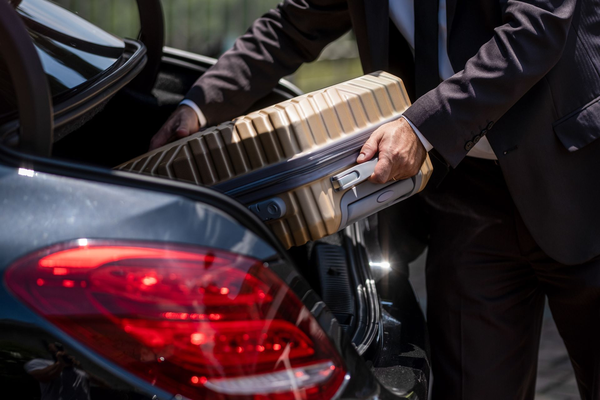 Une personne charge une valise dans un coffre de voiture