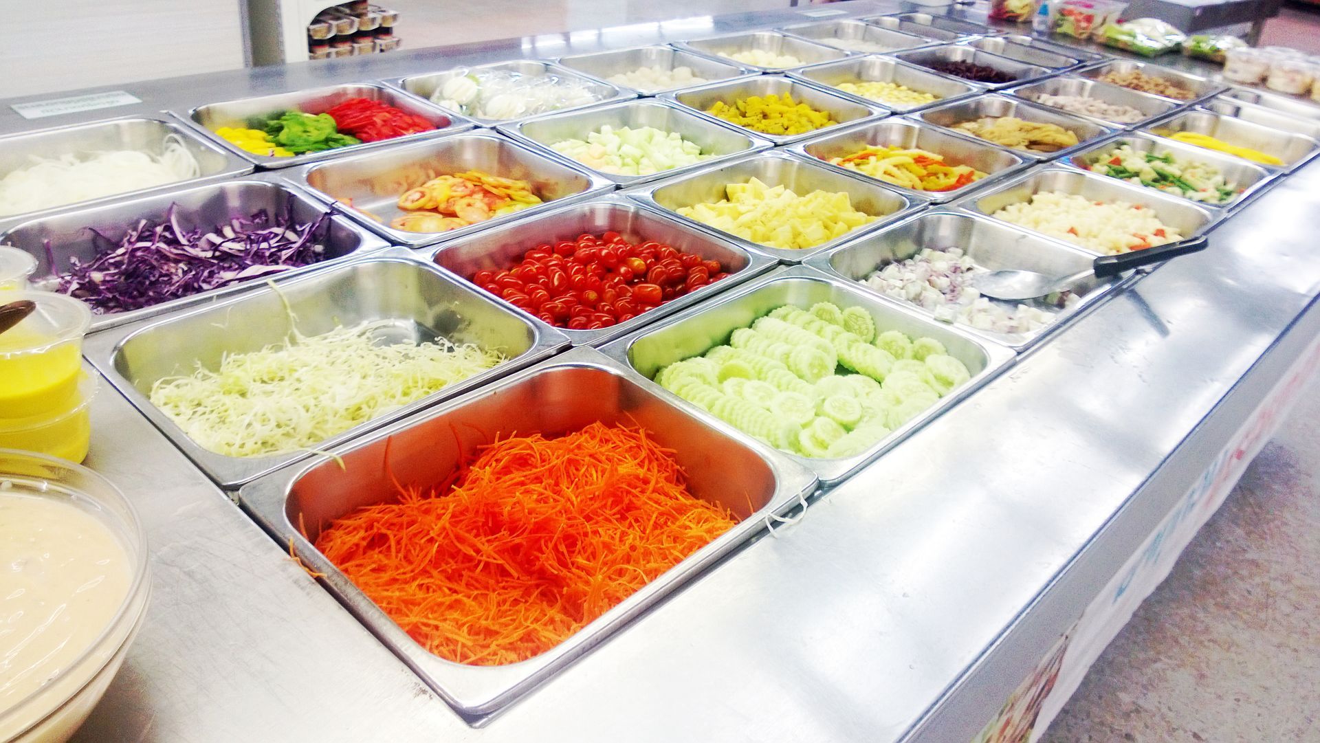 Comptoir de plateaux remplis de légumes colorés coupés en morceaux dans un buffet.