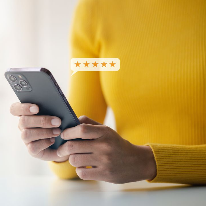 Une personne tenant un smartphone avec une icône de note cinq étoiles.
