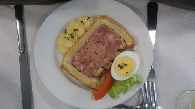Sur une table, une assiette contenant du pâté en croûte, de la mayonnaise et une moitié d'œuf dur