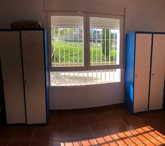 Una habitación con taquillas azules y una ventana grande.