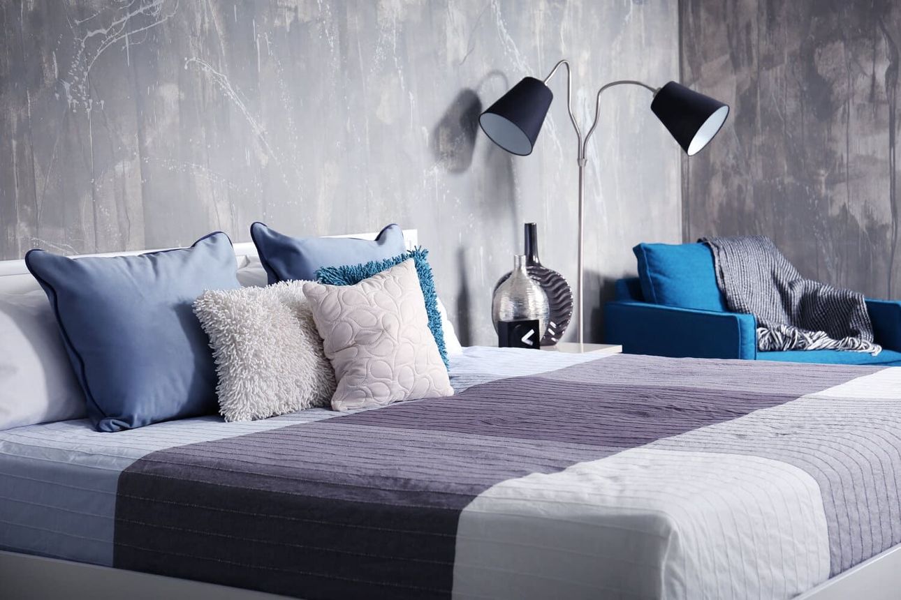 Un dormitorio con una cama, una silla y una lámpara.