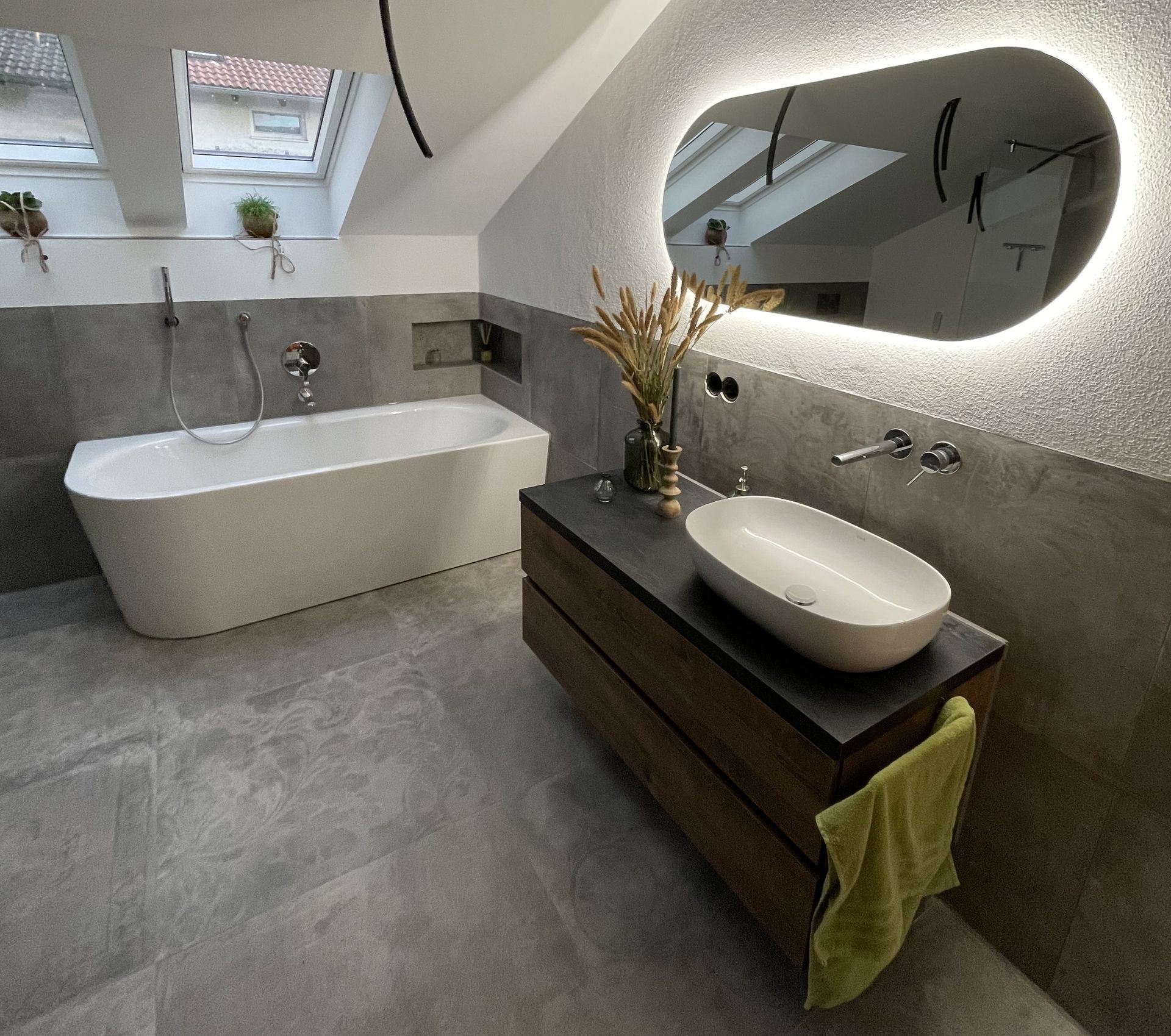 Badezimmer mit Badewanne, Waschbecken und beleuchtetem Spiegel