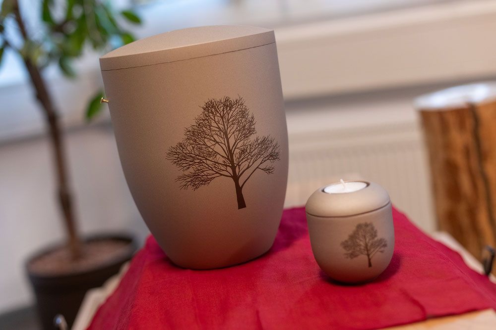 Auf einem Tisch stehen zwei Urnen mit Bäumen darauf.