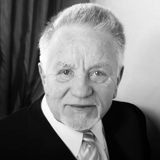 Ein Schwarzweißfoto eines älteren Mannes in Anzug und Krawatte.
