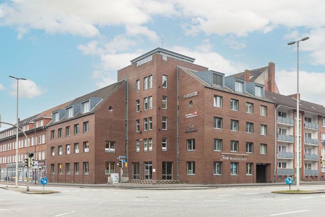 An einer Straßenecke steht ein großes Backsteingebäude.