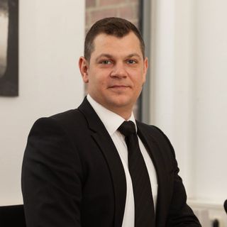 Ein Mann in Anzug und Krawatte lächelt in die Kamera