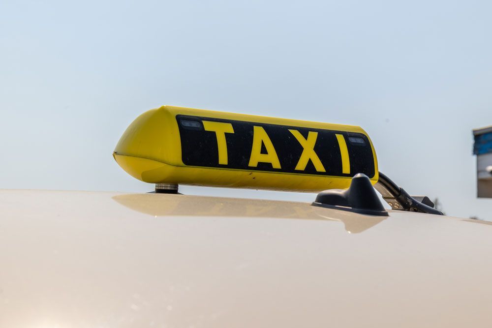 Ein schwarzer Mercedes Benz mit einem gelben Taxischild darauf.