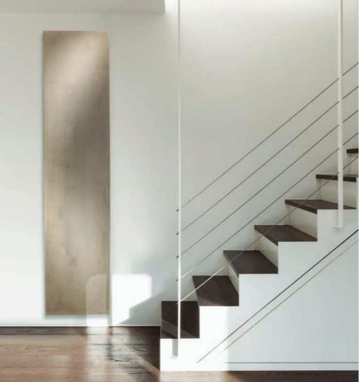 Un radiateur au design contemporain avec finition béton ciré beige en bas d'un escalier intérieur