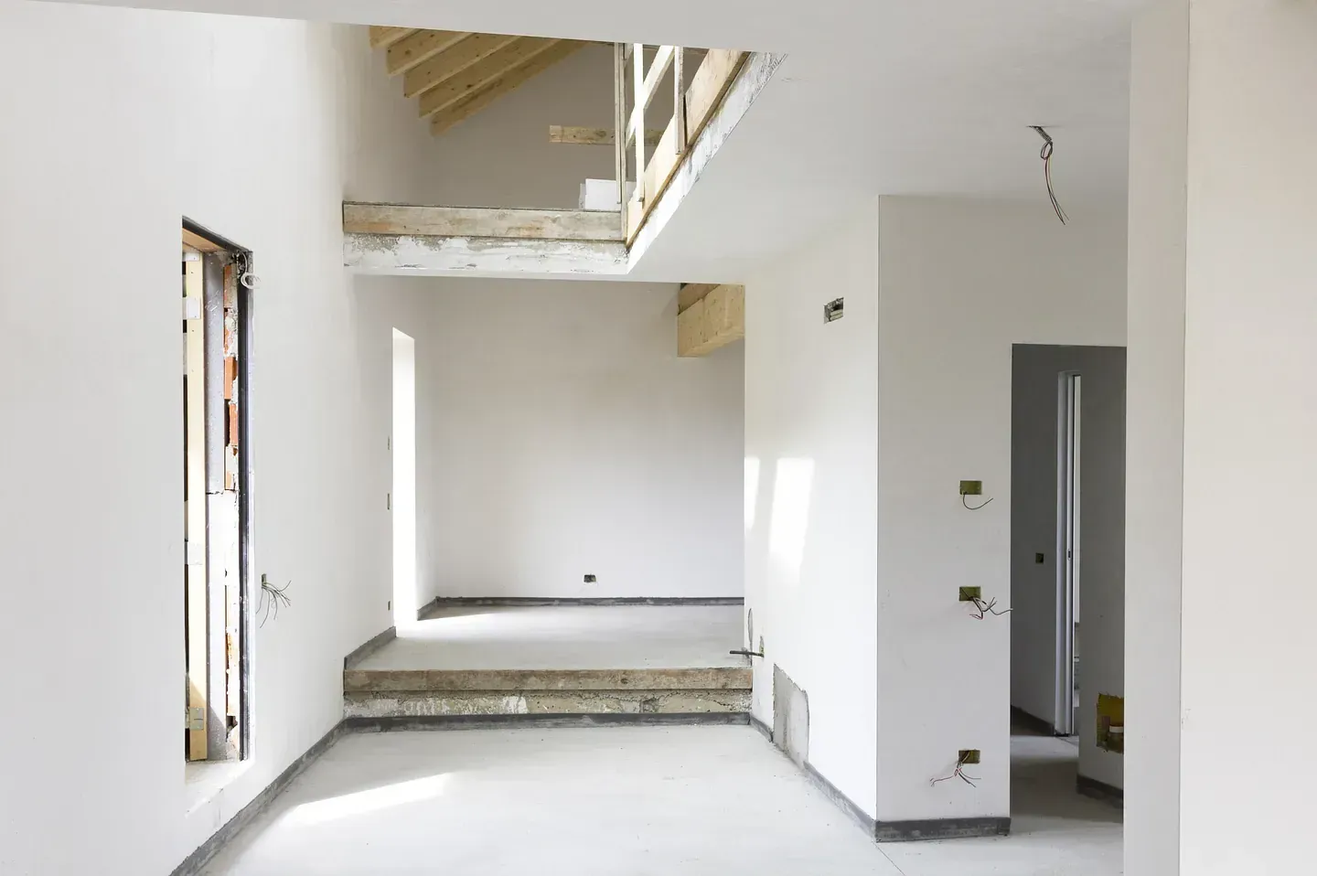 Una habitación vacía con paredes blancas y un techo de madera.