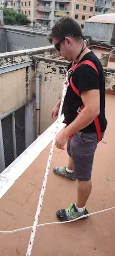 Un hombre está parado en un tejado sosteniendo una cuerda.