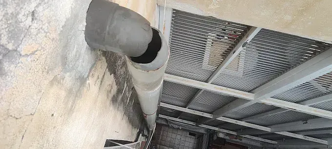 Una tubería cuelga del costado de un edificio.