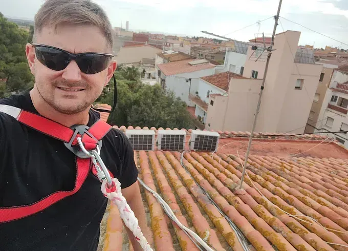 Un hombre que lleva gafas de sol y un arnés está de pie sobre un tejado.