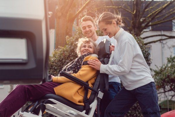 Pflegehaus Kahlenshof GmbH & Co.KG – Ein Mann und eine Frau helfen einer Seniorin im Rollstuhl in ein Fahrzeug