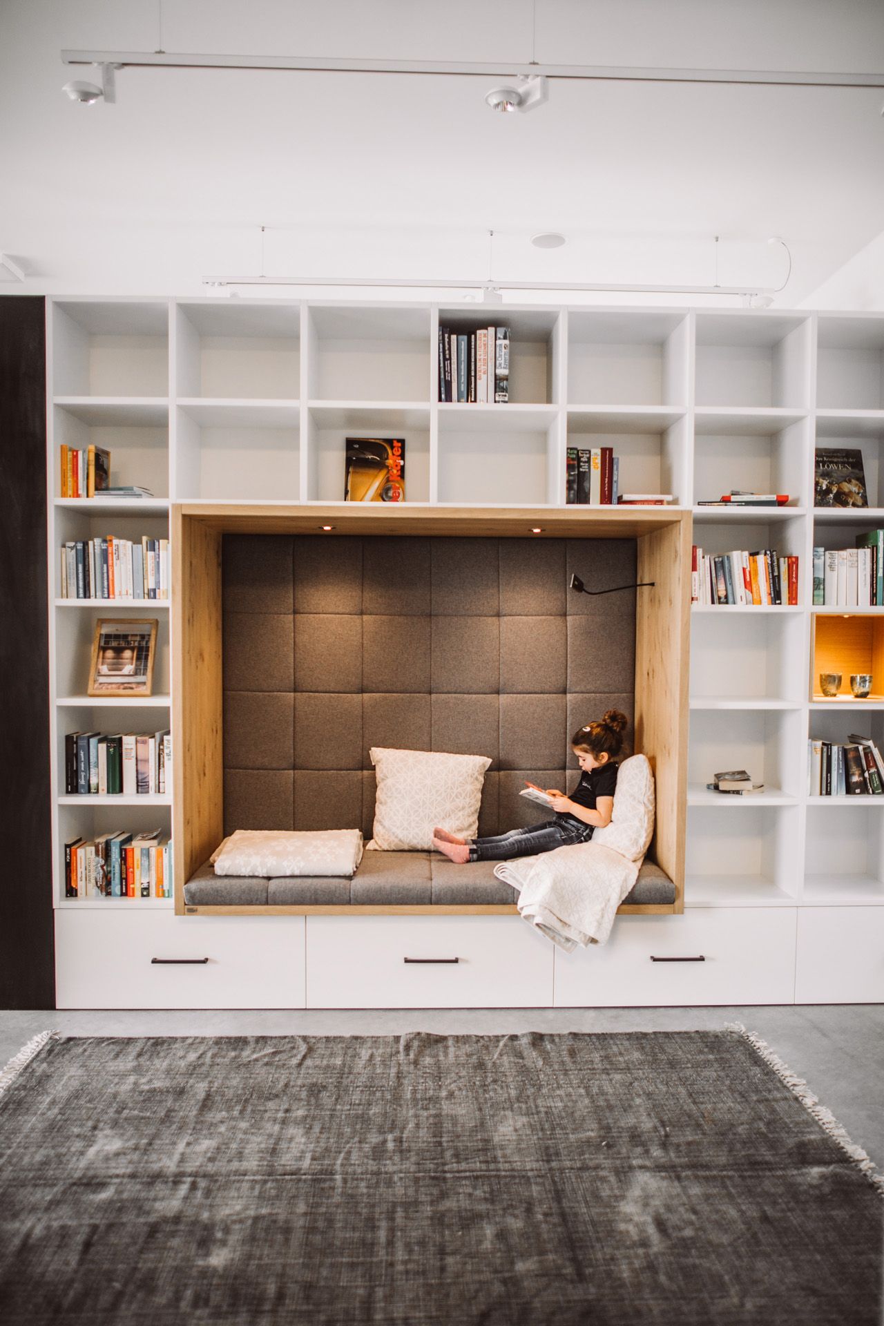 Showroom Häckl - großes Bücherregal, Schrankwand mit Lesenische, Mädchen liest darin