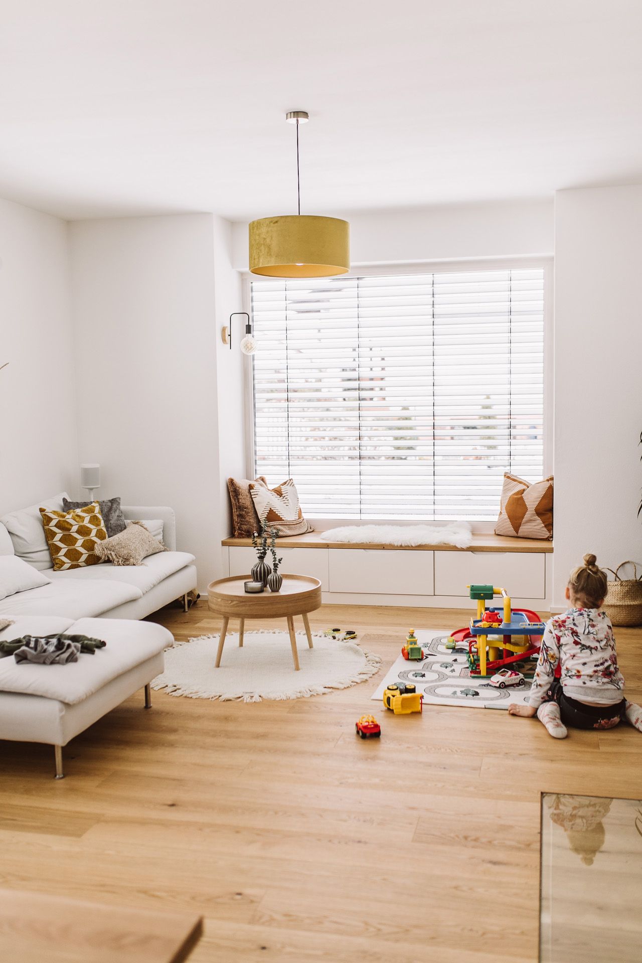Ein Mädchen spielt in einem Wohnzimmer mit individueller Lese-Nische im Fenster