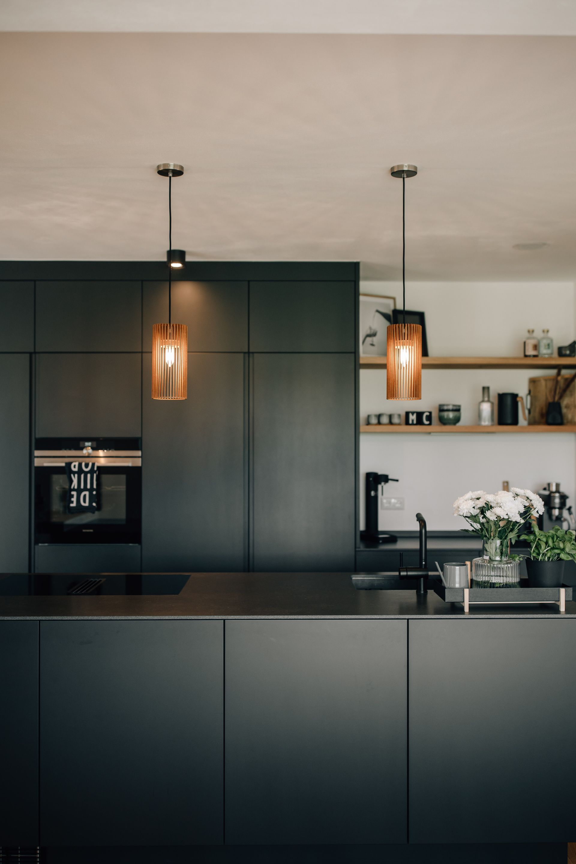 Moderne dunkle Küche mit Akzentlampen und Holzablage