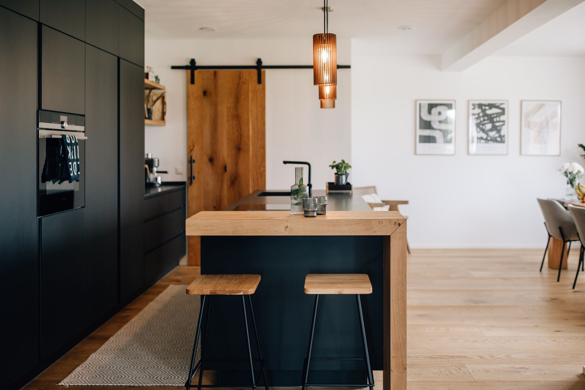 Moderne dunkle Küche mit Akzentlampen und Holztresen