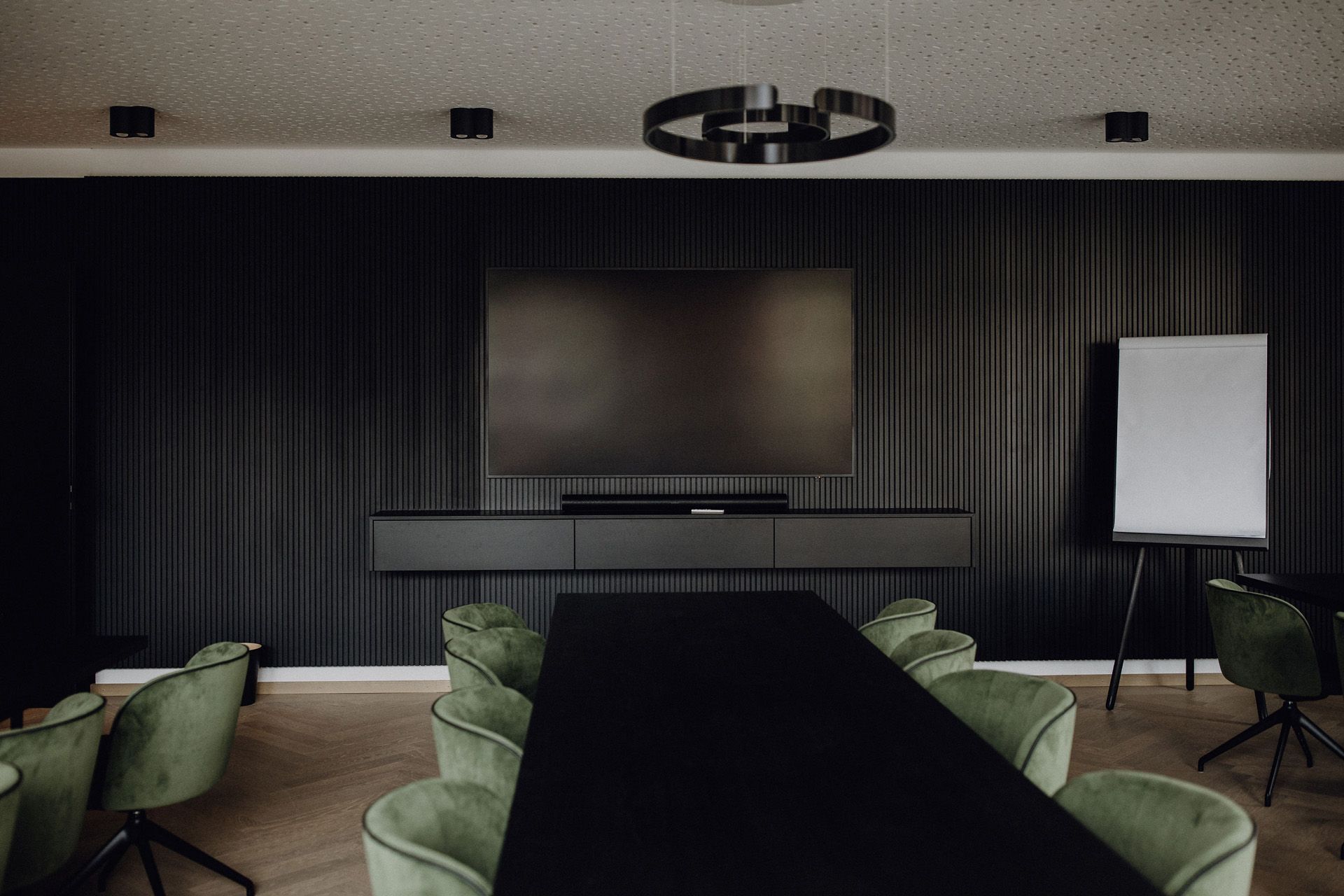 Schreinerei Häckl - hochwertiger Konferenzraum mit langem schwarzen Tisch und schwarz vertäfelten Wänden