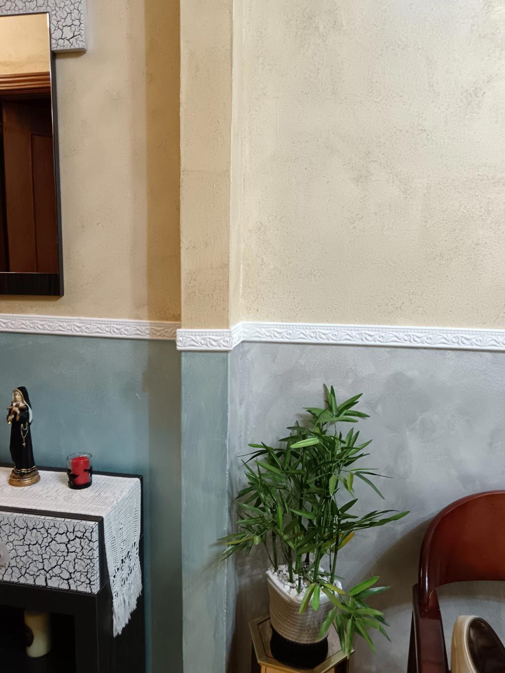 Un rincón de una habitación con una planta y un espejo.