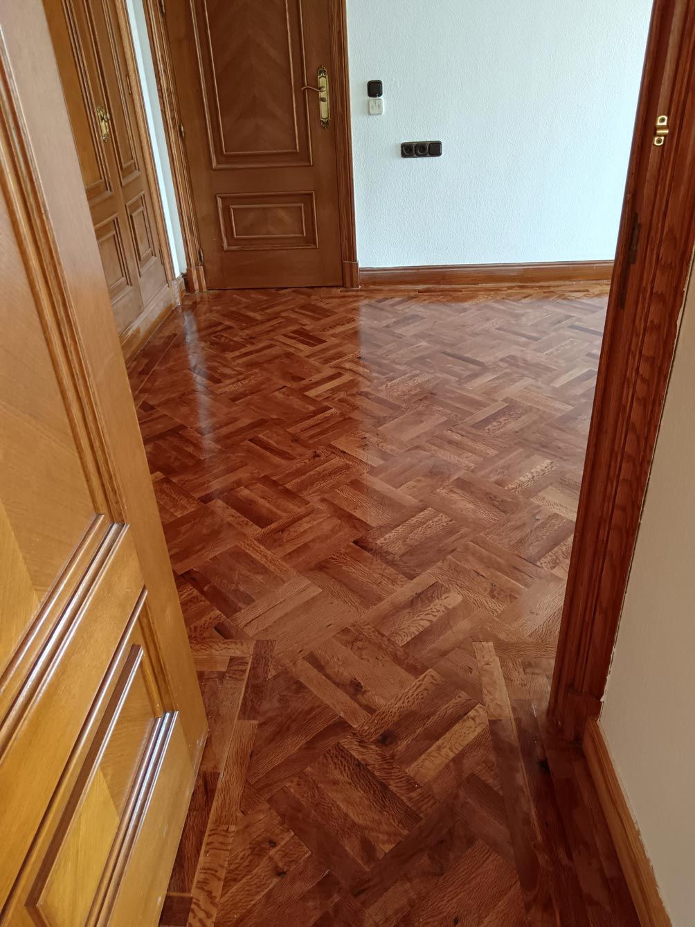 Un pasillo con suelo de madera y una puerta.
