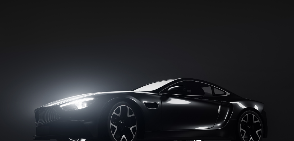 Une voiture de sport noire est garée dans le noir avec ses phares allumés.