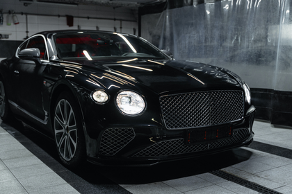 Une Bentley Continental GT noire est garée dans un garage.