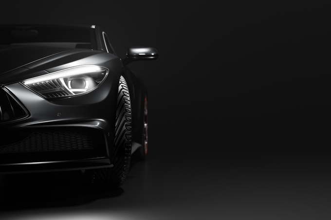 L'avant d'une voiture noire est éclairé dans l'obscurité.