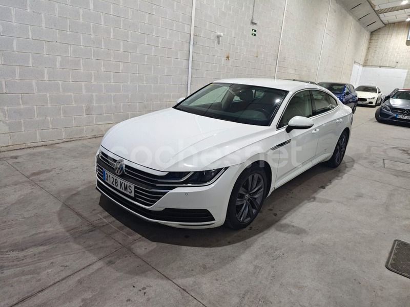 Un sedán Volkswagen Arteon blanco estacionado en un garaje cubierto con paredes y suelo de hormigón.