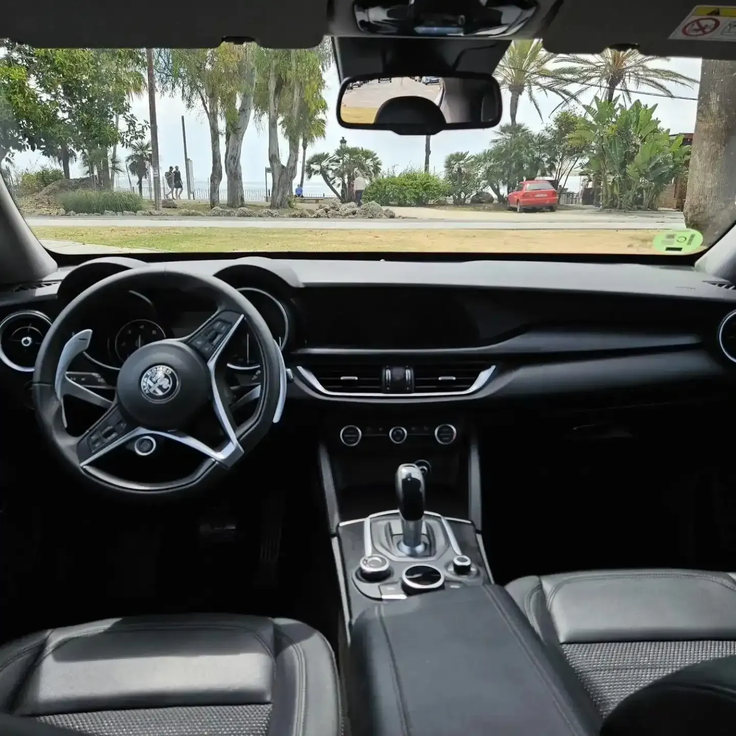 Vista interior desde el asiento del conductor de un Alfa Romeo, que muestra el salpicadero, el volante.