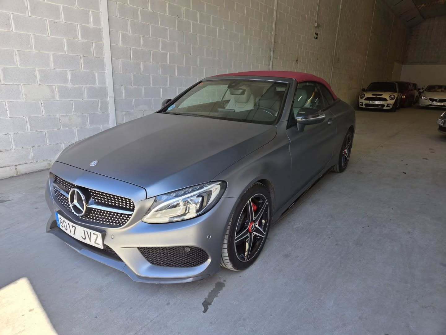 Un Mercedes-Benz descapotable de color gris mate estacionado dentro de un almacén de hormigón.