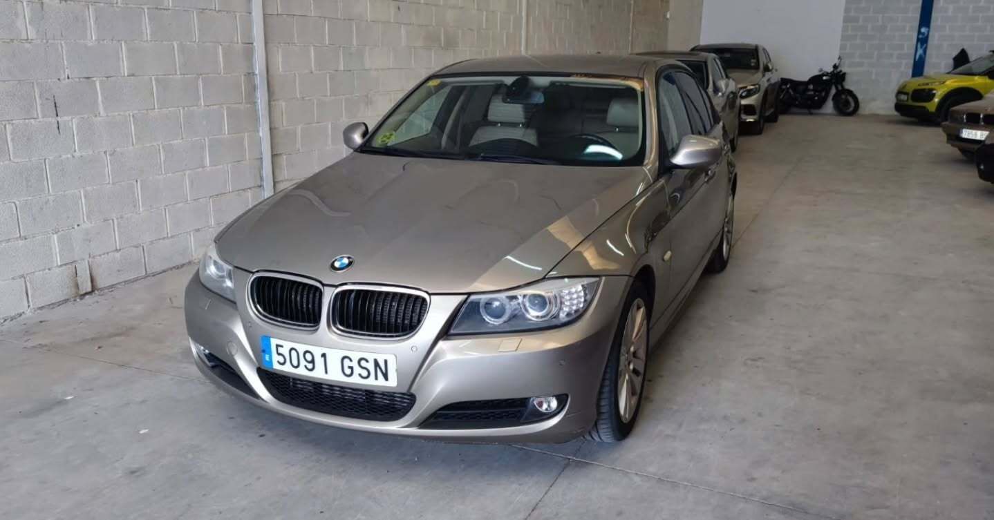 Un sedán BMW de color bronce estacionado en un garaje cubierto, inclinado hacia la parte delantera izquierda.