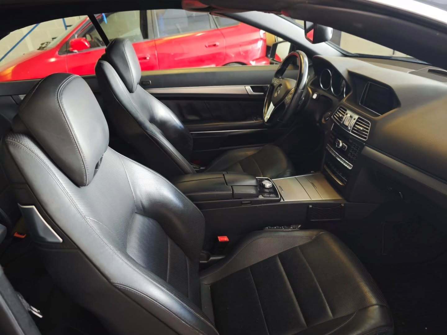 Interior de cuero negro de un coche descapotable de lujo, mostrando los asientos delanteros y el salpicadero.