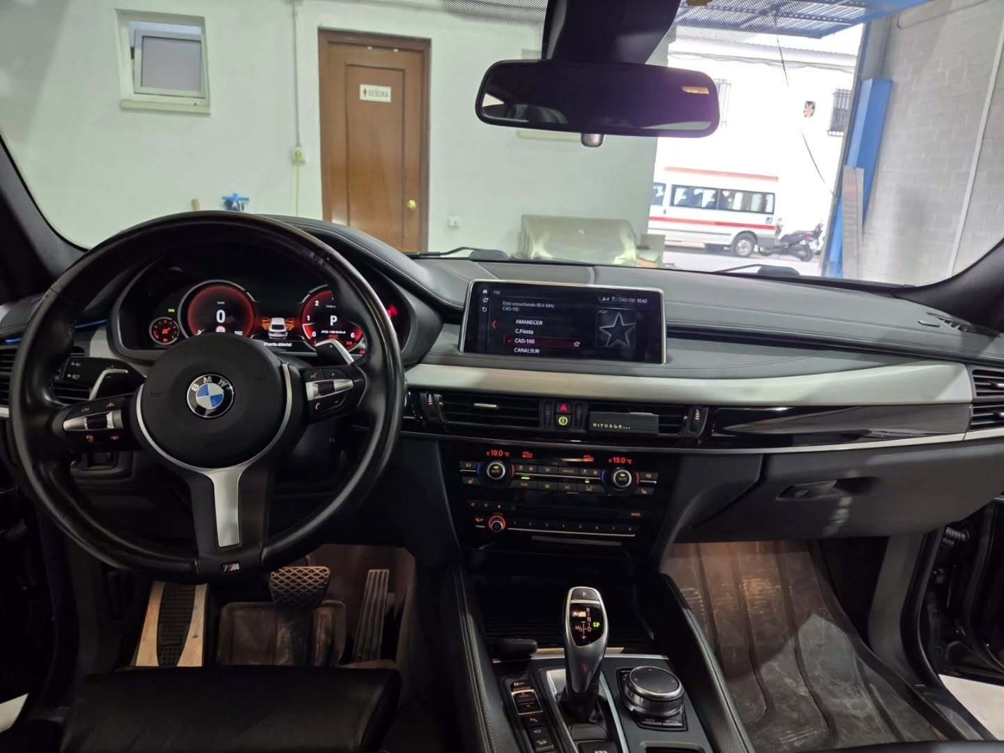 Vista interior desde el asiento del conductor de un BMW negro, donde se aprecian el salpicadero, el volante.