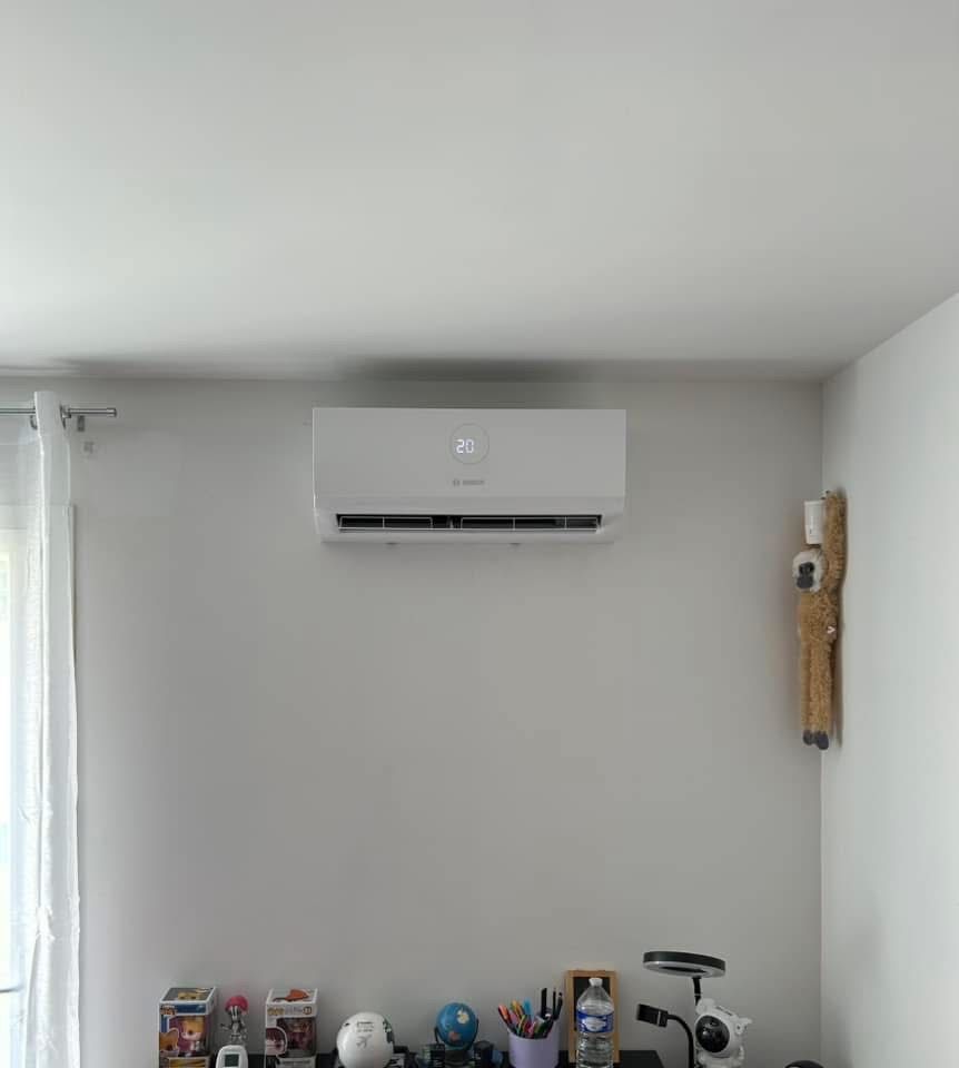 Chambre minimaliste avec un climatiseur mural au-dessus d'une étagère contenant de petits objets.