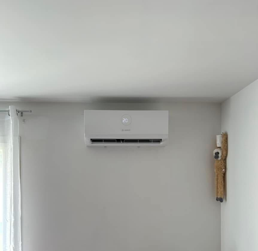 Mur blanc avec un climatiseur mural et un petit objet décoratif sur le côté droit.