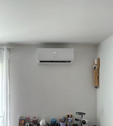Chambre minimaliste avec un climatiseur mural au-dessus d'une étagère contenant de petits objets.