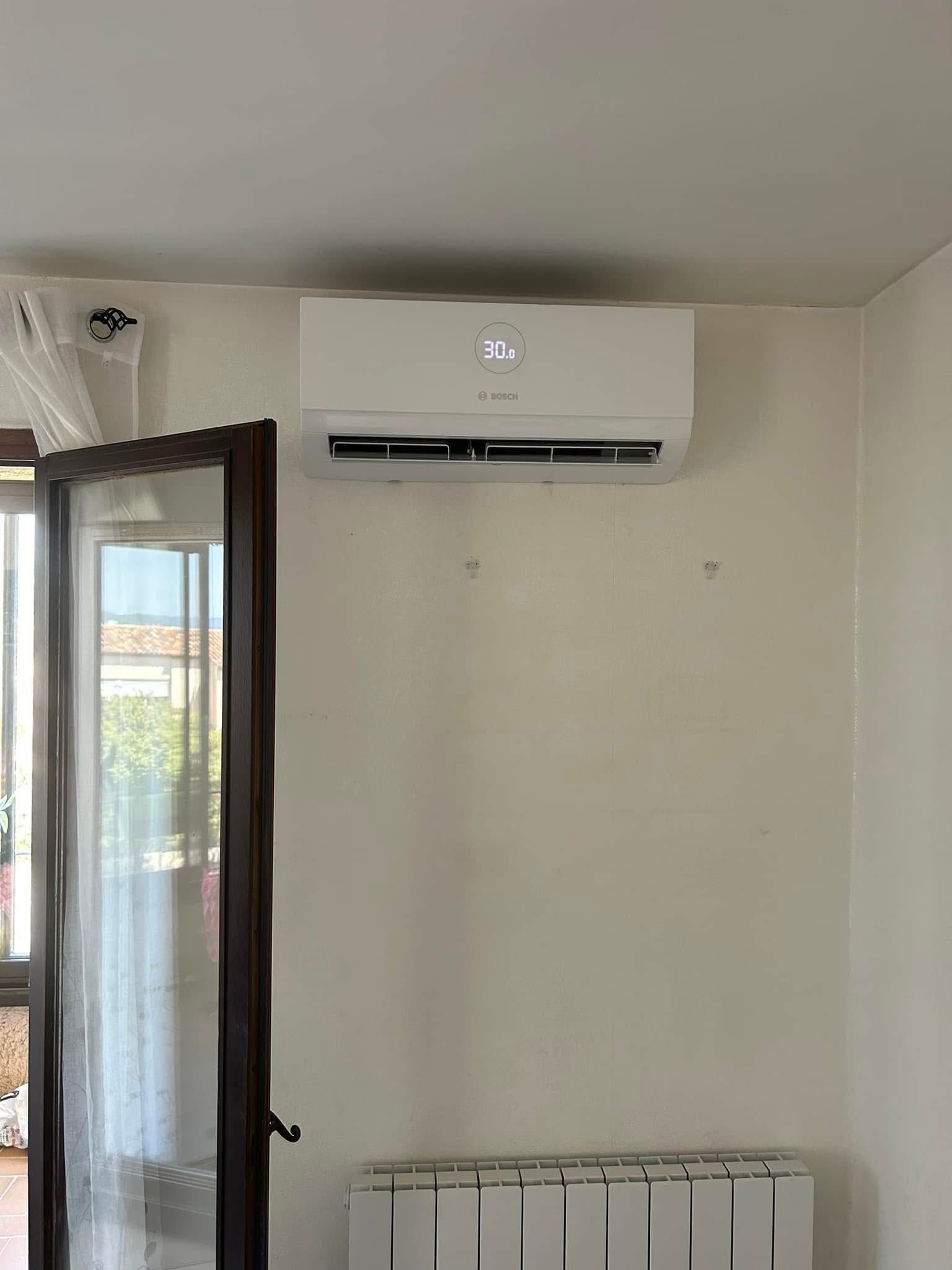 Mur intérieur avec un climatiseur mural et une fenêtre ouverte à côté d'un radiateur.