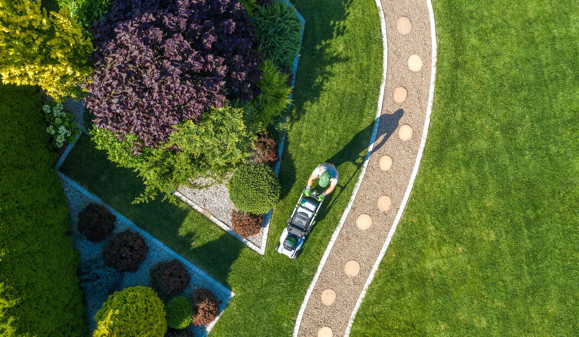 Vue du ciel d'un paysagiste qui passe la tondeuse dans un jardin.