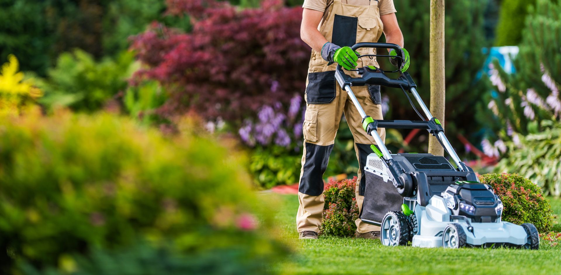 Un paysagiste qui passe la tondeuse dans un jardin.