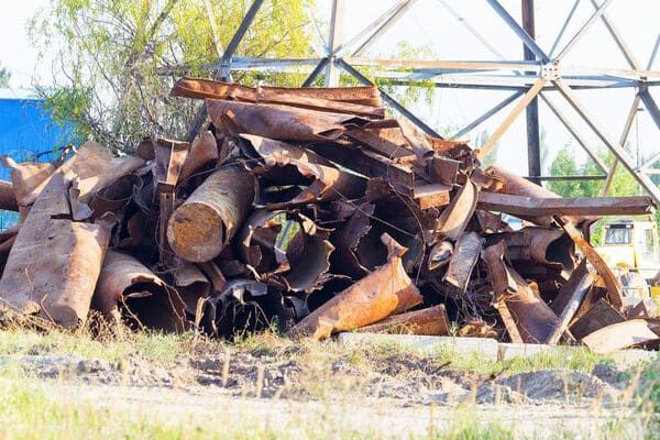 Una pila de tubos de metal oxidados yace en el césped.