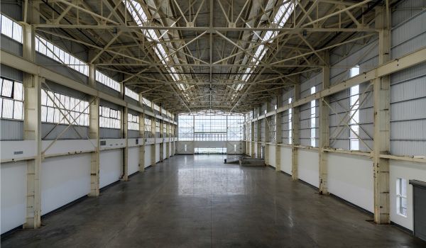 Un gran almacén vacío con muchas ventanas y un techo.