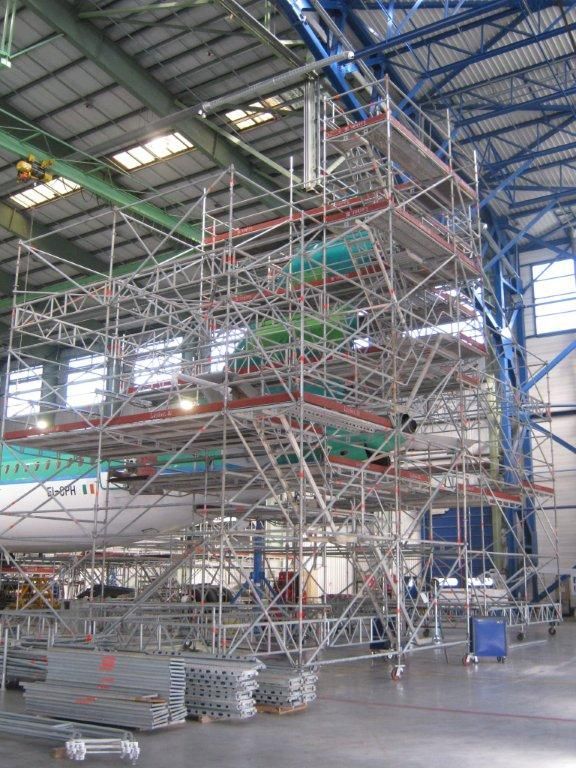 Échafaudages entourant un avion dans un hangar, pour des travaux de maintenance