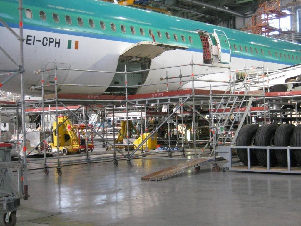 Un avion en réparation dans un hangar, entouré d'échafaudages