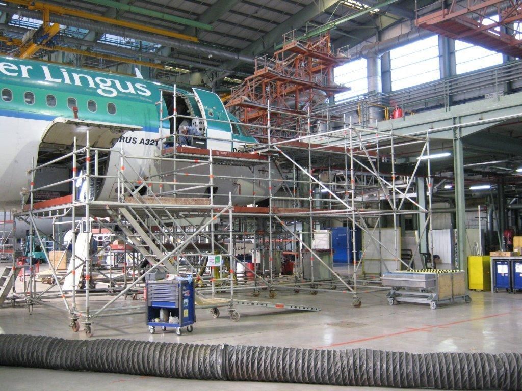 Un avion d'Aer Lingus dans un hangar de maintenance, entouré d'échafaudages