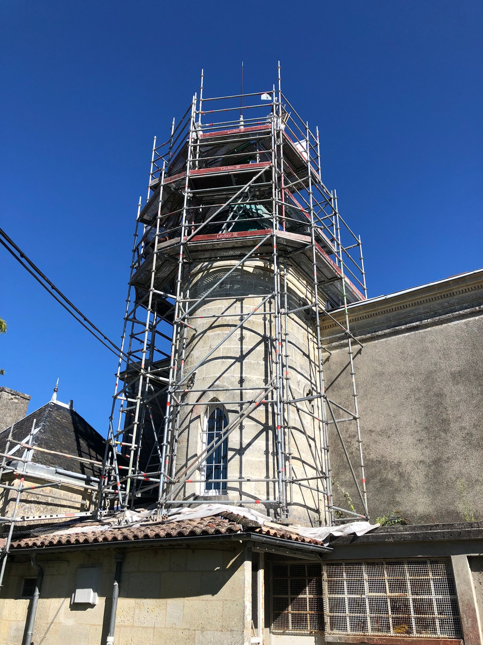 Des échafaudages entourent une tour en pierre sur un bâtiment
